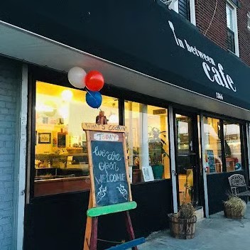 In Between Cafe storefront on a sunny morning with sidewalk A-frame chalkboard